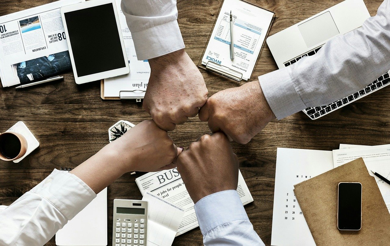 4 hands together over business papers