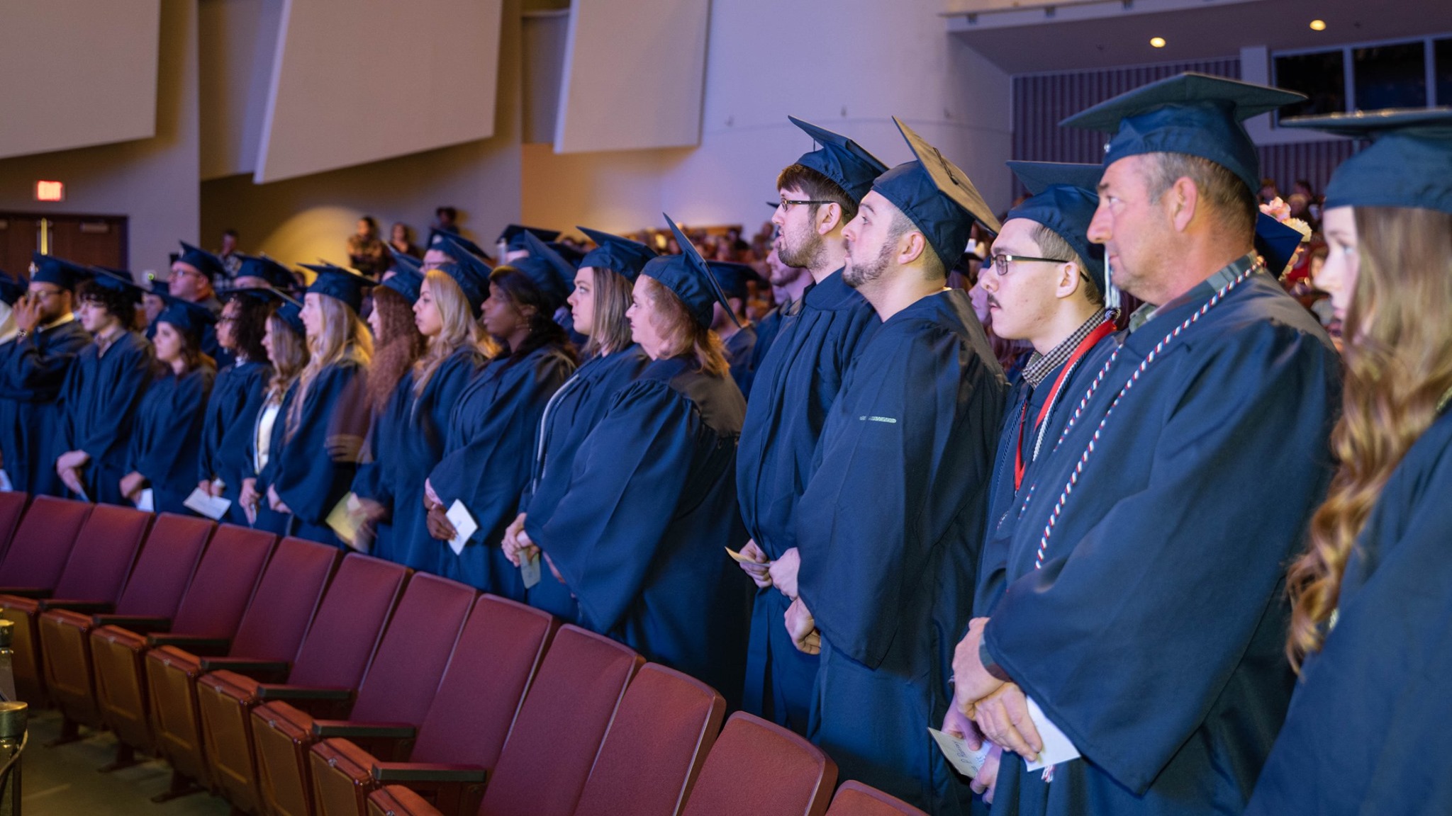 Madisonville graduates in auditorium wearing gowns