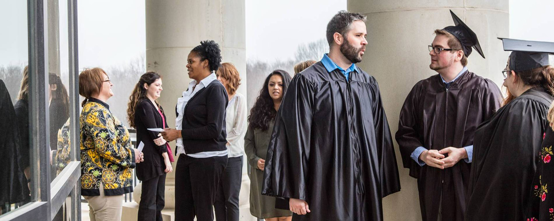 Southcentral grads in regalia standing and speaking to each outside