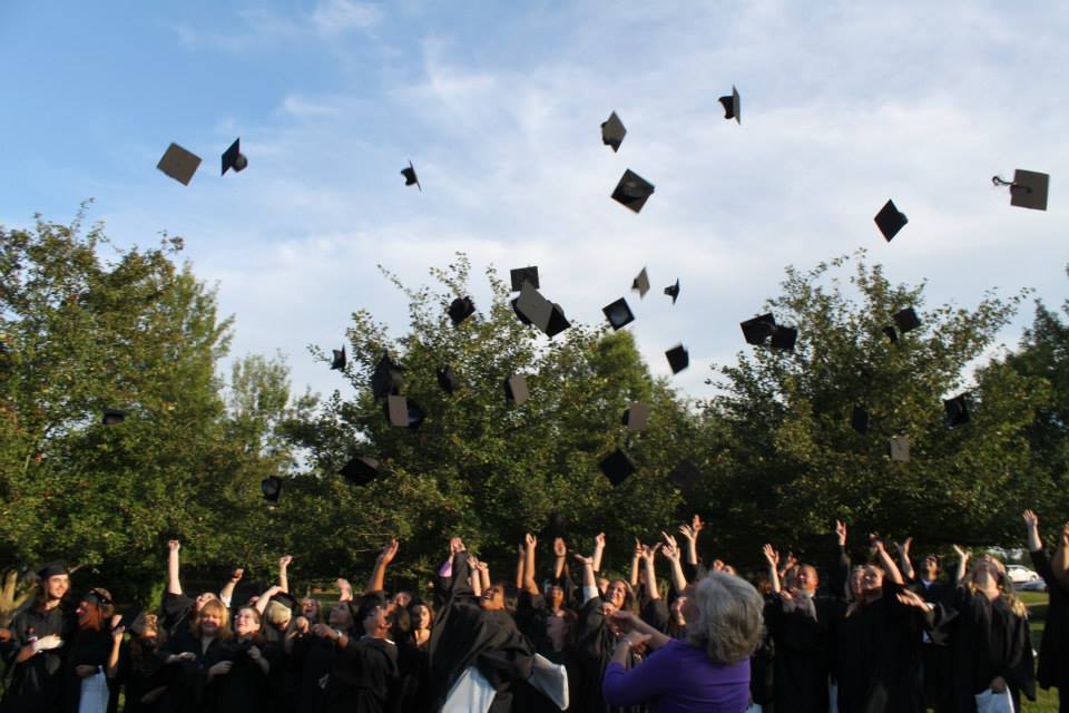 OCTC students in gowns throwing graduation caps